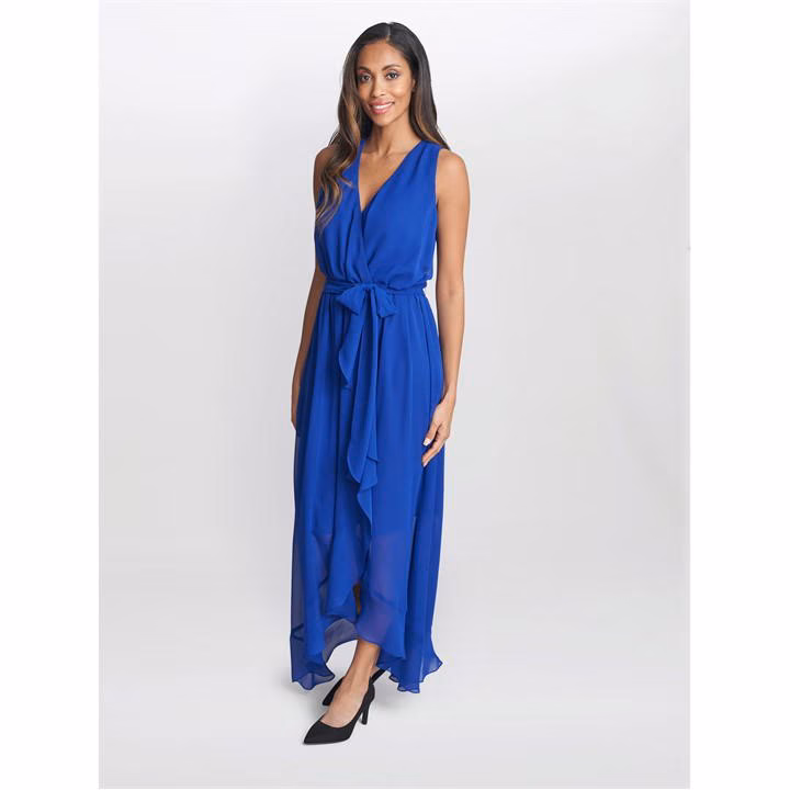 Woman wearing cobalt blue sleeveless wrap dress with ruffled hem and black heels, standing confidently