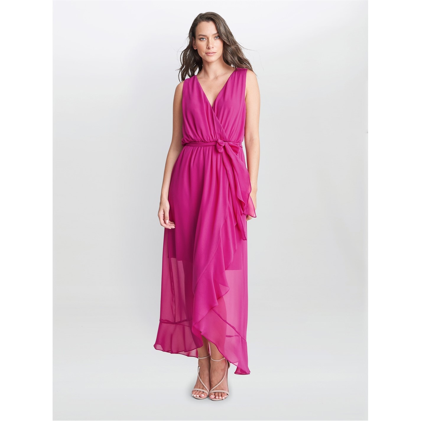 Woman in fuchsia Gina Bacconi wrap dress with ruffled asymmetric hem, exuding quiet elegance