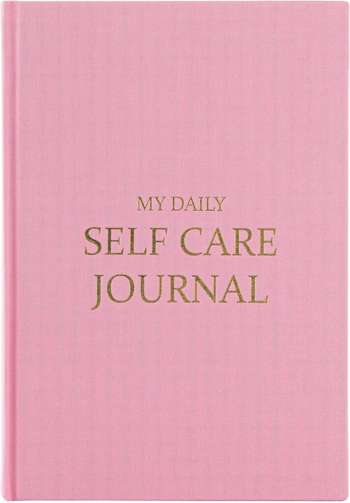 Pink hardcover My Daily Self Care Journal with gold embossed text — a guided journal for wellness and daily reflection.