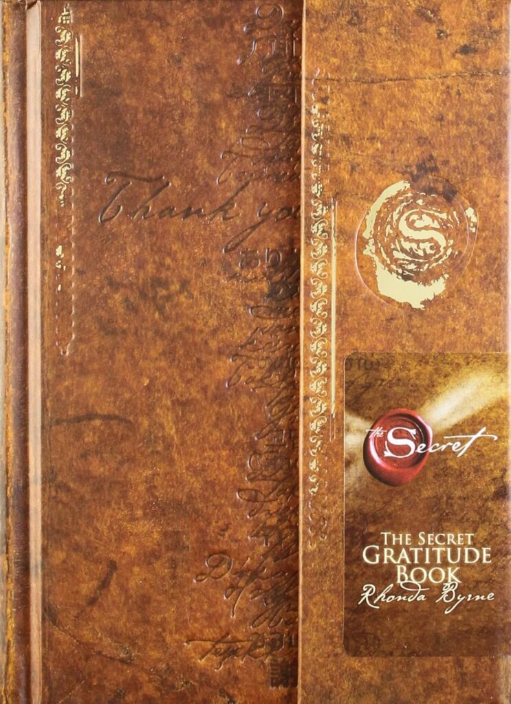 Embossed brown leather-style cover of The Secret Gratitude Book by Rhonda Byrne, with gold detailing and wax seal design.