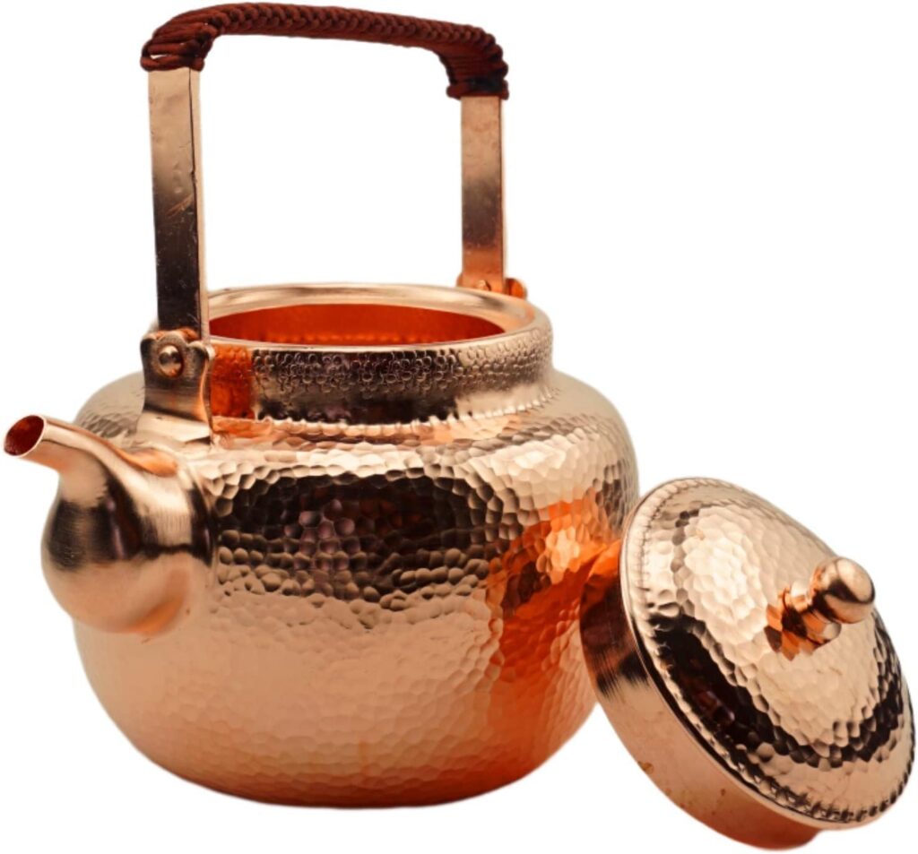 Handmade solid copper teapot with hammered finish and open lid, featuring a woven handle grip.