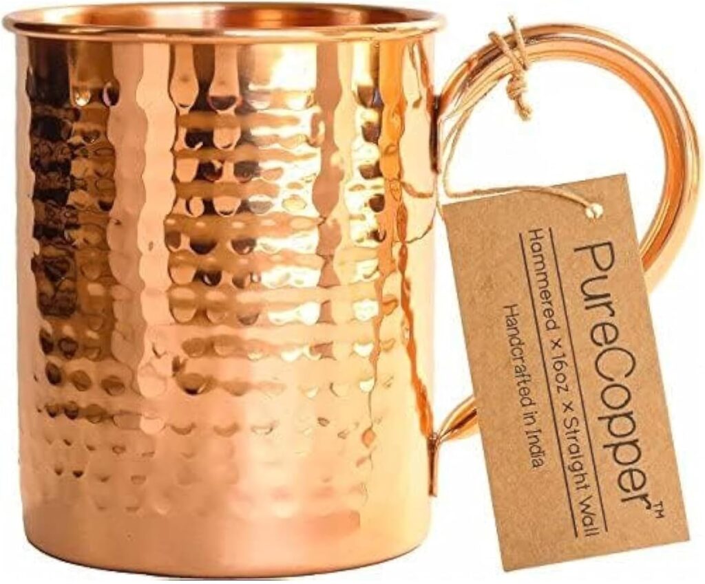 Handcrafted hammered pure copper mug with label tag, upright on white background.