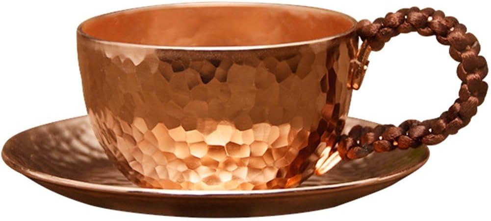 Hammered pure copper tea cup and saucer with braided handle on white background.