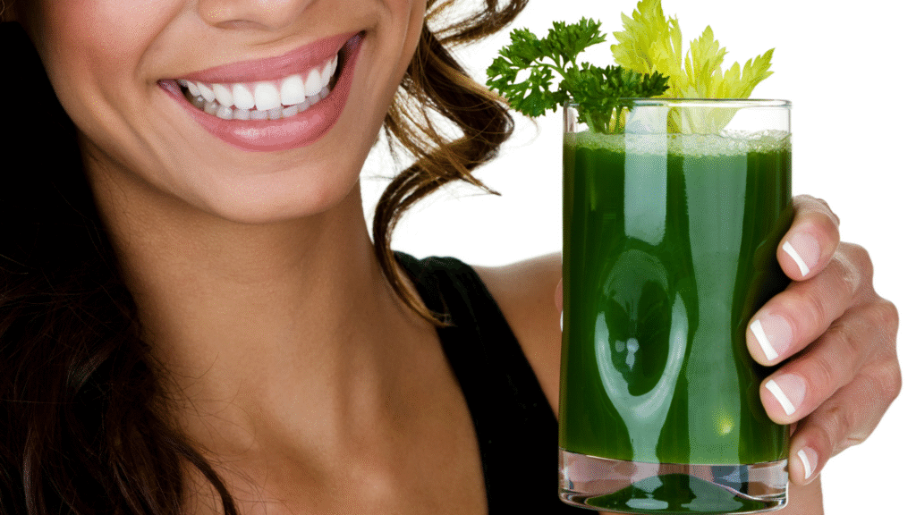 Woman smiling and holding a green juice with leafy garnish, symbolising nourishing choices