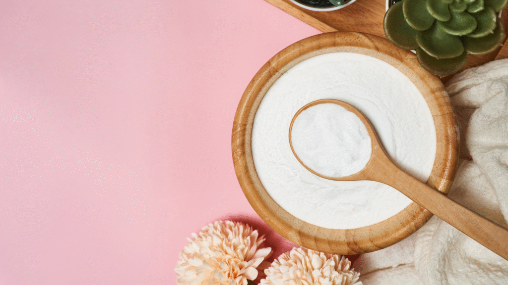 Collagen powder in a wooden bowl with scoop on soft pink background, symbolising skin nourishment and inner healing