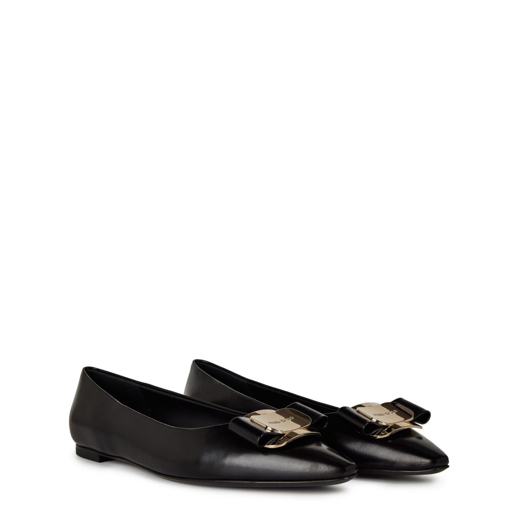 Black Ferragamo New Vara ballet flats with signature grosgrain bow and gold logo plate, photographed on a white background.